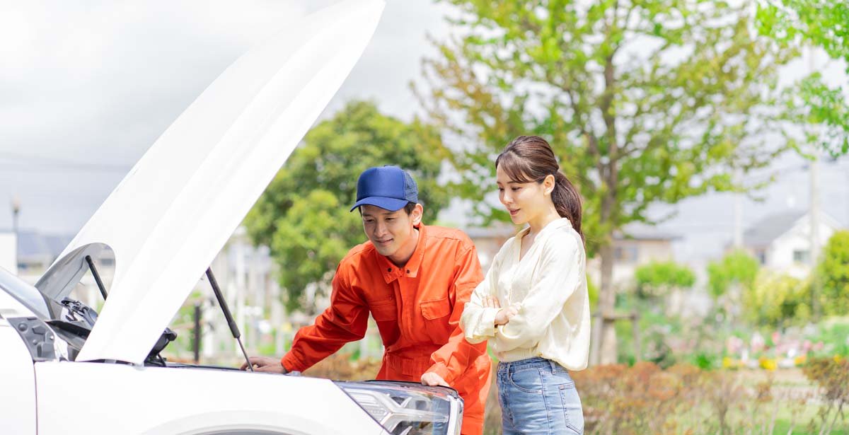 車の点検をする作業員と女性