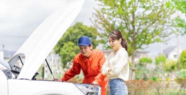 車の点検をする作業員と女性