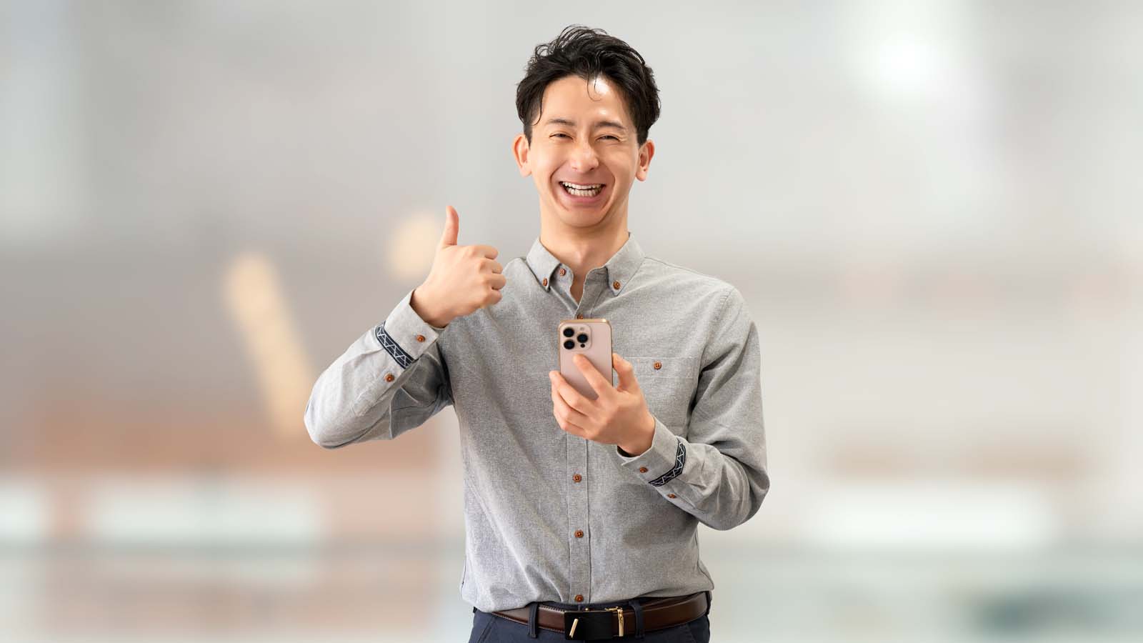 スマートフォンを持っていいね！のポーズをする男性