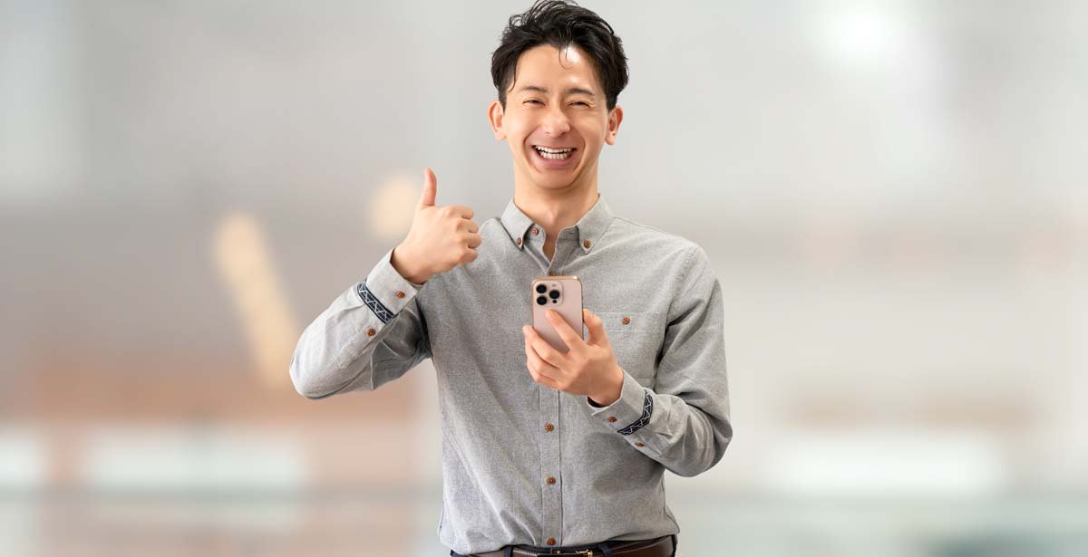 スマートフォンを持っていいね！のポーズをする男性