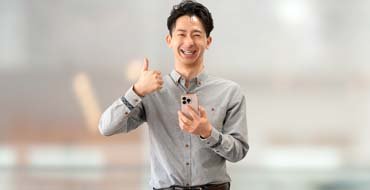 スマートフォンを持っていいね！のポーズをする男性