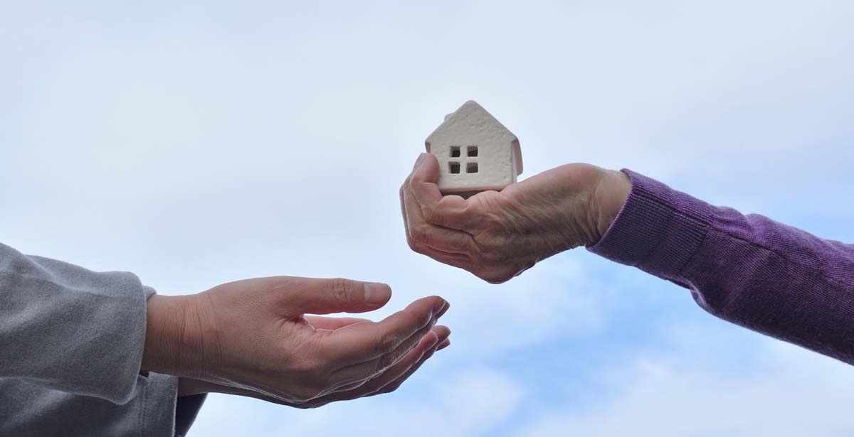 家の模型を高齢の親から子に手渡しする画像