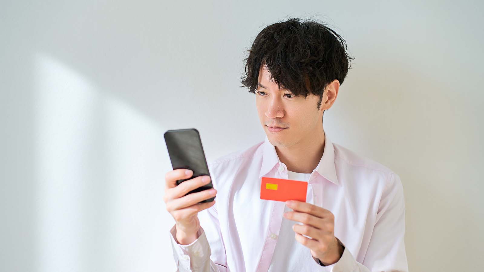 カードを持ってスマートフォンを操作する男性