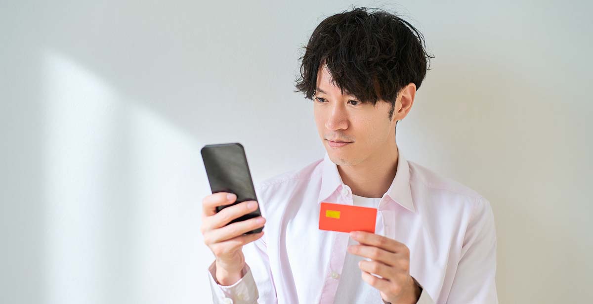 カードを持ってスマートフォンを操作する男性