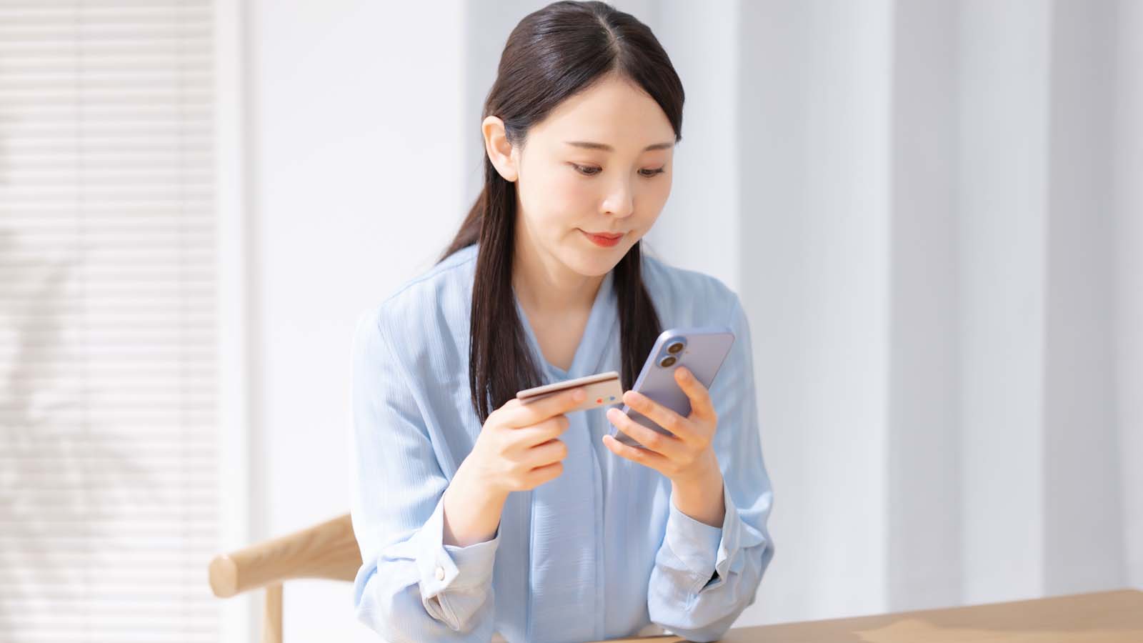 カードとスマホを持つ女性