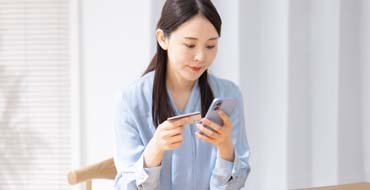 カードとスマホを持つ女性