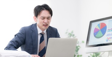 困った表情で仕事をする男性