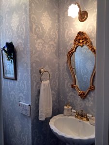 トイレには、憧れのペデスタルシンク（足付き洗面台）とイメージ通りの鏡を設置。壁紙はローラアシュレイ