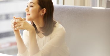 テーブルに座って手を組んでいる女性の画像