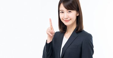 人差し指を立てるスーツの女性の画像