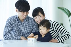 両親と子供が小さな家を見ている画像