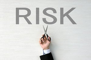 RISKの文字の下でスーツの人がハサミを持っている画像