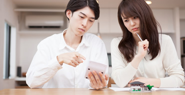 電卓を持っている男性とペンを持っている女性が考えている画像