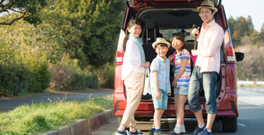 車のトランクの前で両親と2人の子供が立っている画像