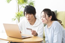 PCを見ながらカードを持っている男性と女性の画像