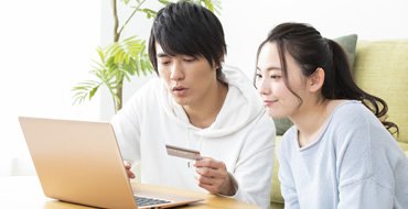 PCを見ながらカードを持っている男性と女性の画像