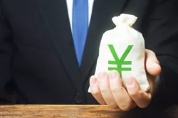 お金の袋を手に持っているスーツの男性の画像