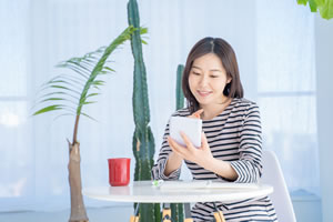 女性がテーブルに座って電卓を見ている画像