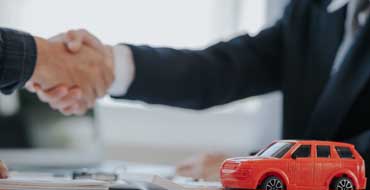 握手をする人たちの前に置かれた車の模型