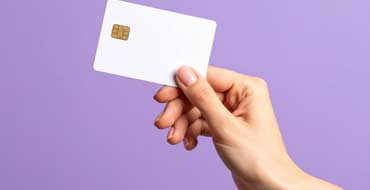 紫の背景の前で白いカードを持つ手